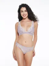 Conjunto de ropa interior lila con detalles de encaje blanco, compuesto por un bralette triangular con breteles regulables y una bombacha tipo tanga.