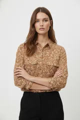 Camisa de viscosa con estampado floral en tonos tierra, cuello clásico, cierre frontal con botones y dos bolsillos delanteros con solapa.