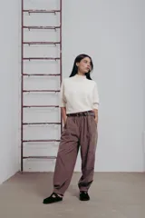 Pantalón de corte amplio color marrón, con cintura elastizada, detalle de botones en los laterales y cinturón incluido.