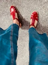 Sandalias rojas de cuero con tiras anchas y hebilla al tobillo.