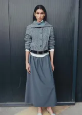 Cárdigan gris de tejido de punto grueso con diseño trenzado, cuello camisero, cierre frontal con botones y terminaciones acanaladas.