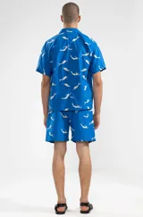 Camisa azul con estampado de sirenas blancas, de corte recto, manga corta y cuello camisero.