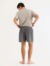 Conjunto de pijama para hombre compuesto por una remera azul marino de manga corta con cuello en V y un short a cuadros en tonos azul, gris y blanco.