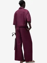 Camisa boxy color borgoña de algodón orgánico, con cuello solapa, manga corta sobre el codo, botonadura frontal, bolsillo en el pecho, canesú en la espalda y ceñidor con cordón en el bajo.