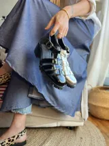 Sandalias de cuero con plataforma y múltiples tiras horizontales. Un par es de color negro charol y el otro plateado.