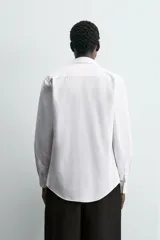 Camisa blanca de manga larga, corte slim fit, con cuello italiano y cierre frontal de botonadura.