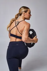 Top deportivo color beige con banda inferior azul y tirantes finos azul marino. Espalda cruzada con doble tira.