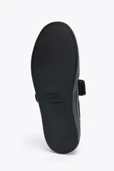 Zapato plano tipo bailarina en tejido color negro. Detalle de pespunte en el cuerpo, tira con adhesivo ajustable, suela engomada y acabado en punta redonda.