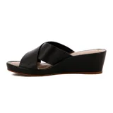 Sandalia tipo mule de plataforma corrida (wedge), color negro, con tiras anchas cruzadas sobre el empeine. Presenta un pequeño detalle metálico dorado en el lateral de la tira superior.