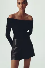 Falda pantalón corta negra de cuero sintético, tiro medio y corte cruzado.