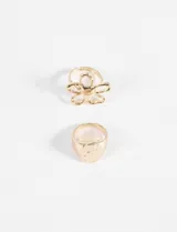 Set de dos anillos dorados, uno con forma de flor y otro con forma de sello con superficie texturizada.
