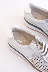 Zapatillas acordonadas color dorado con capellada de cuero calado, base blanca y detalles en cuero blanco en el talón.