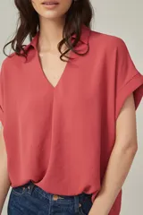 Blusa color salmón de viscosa, corte holgado, con cuello camisero y mangas cortas con dobladillo.