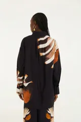 Camisa negra con estampado de amonitas, cuello mao, botones frontales ocultos y mangas largas ligeramente acampanadas.