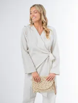 Conjunto color beige de lino, compuesto por un blazer cruzado con lazo para atar y un pantalón de corte recto con cintura elástica.