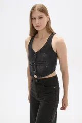 Chaleco de jean celeste sin mangas, con cuello en V, cierre frontal con botones y dos bolsillos con solapa en el pecho.