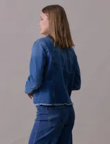 Campera de jean azul de la marca Baccini, con cuello solapa, abertura central con botones metálicos, bolsillos delanteros y ruedo desflecado.