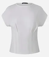 Blusa blanca de algodón con cuello redondo y mangas cortas. Presenta pliegues delanteros y traseros con efecto corsetado.