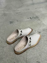 Sueco de cuero negro con detalle de apliques metálicos triangulares plateados.