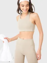 Top deportivo color beige con espalda de diseño único y almohadillas removibles.
