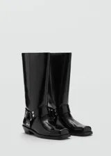 Bota alta de caña recta color negro charol, con apliques metálicos y punta cuadrada.