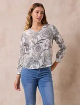 Blusa de gasa marca Sioni, color blanco con estampado floral en tonos grises. Tiene escote en V y mangas largas con puño.