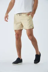 Short de baño color arena con estampado geométrico en tonos celeste y blanco. Cuenta con cintura elástica ajustable con cordón, dos bolsillos laterales, un bolsillo trasero, suspensor interno y logo bordado.