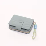 Billetera celeste con cierre de cremallera dorada y detalle de costuras en forma de hojas.