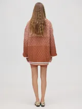 Cardigan tejido de punto con patrón de rombos en degradé de grises y blanco. Tiene corte oversize, mangas largas y cierre frontal con botones.