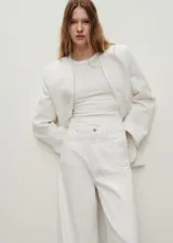 Pantalón de jeans blanco, tiro alto, corte wideleg (pierna ancha) y largo completo. Presenta cinco bolsillos y cierre frontal con botón y cremallera.