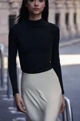 Camiseta blanca de manga larga con cuello alto y corte ajustado.