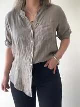 Camisa de lino color gris, con botones frontales y corte relajado, ideal para climas cálidos.