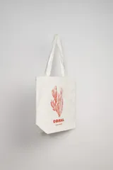 Tote bag blanca con estampado de un caballito de mar en color naranja y texto en la parte inferior.