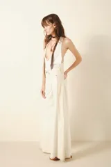 Pantalón de jean color crudo, corte oxford amplio, tiro medio, con cintura y cadera ajustada. Presenta recortes laterales en las piernas que añaden vuelo. Confeccionado en tejido rígido de algodón.