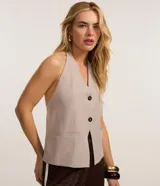 Chaleco color beige con escote halter, corte al cuerpo y cierre frontal con botones. Presenta un bolsillo de ojal en el frente.
