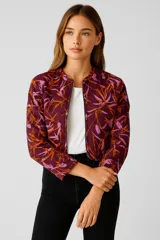 Campera bomber manga larga con estampado de hojas en tonos naranja y rosa sobre fondo borgoña, con cierre frontal y cuello redondo.
