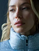 Campera de plumas reversible marca Michael Kors, con un lado liso color celeste y otro lado estampado con el logo de la marca en celeste y blanco. Tiene cierre metálico central, bolsillos delanteros y avíos metálicos con el logo. Incluye bolsa autoportante.