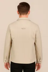 Sobrecamisa color beige con cuello clásico, cierre frontal con botones a tono, mangas largas con puños abotonados, dos bolsillos de parche en el pecho y corte recto.