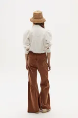 Pantalón de jean acampanado color caramelo, de tiro alto y corte ajustado en la parte superior. Presenta bolsillos delanteros y traseros, y ruedo acampanado con vuelo.