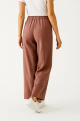 Pantalón de lino color beige, de corte ancho y tiro alto, con bolsillos laterales y cintura elastizada con cordón ajustable.