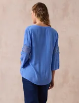 Blusa celeste de gasa bambula con cuello a la base y escote en V. Manga ¾ amplia, con aplique de crochet en los puños.