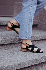 Sandalias negras con tiras cruzadas y tobillera marrón con hebilla dorada. Taco bajo de madera.