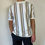 Remera tejida en hilo de algodón a rayas verticales blancas, marrones y grises, de corte semi oversize.