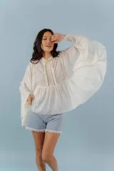 Camisa azul de algodón con cuello alto y mangas largas acampanadas con detalles de puntilla.