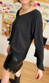 Blusa negra con escote en V y mangas largas acampanadas con volados.