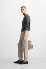 Pantalón color arena de corte recto, confeccionado en tejido elástico. Cuenta con cintura elástica ajustable con cordón, bolsillos laterales y bolsillos de vivo en la parte trasera.