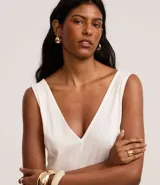 Vestido midi evasé color blanco, sin mangas, con escote en V tanto en la parte delantera como en la espalda, y pences verticales.