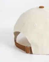 Gorra de béisbol bicolor, con cuerpo de canvas color crema y visera de gamuza color marrón. Tiene bordado frontal con la palabra "Wednesday" y el número "1996".