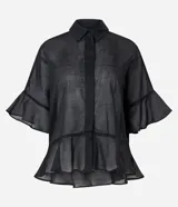 Camisa negra de voile, ligeramente transparente, con cuello camisero, abotonada adelante y mangas cortas con volados amplios.