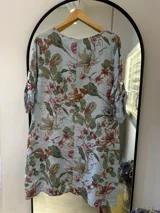 Vestido midi celeste con estampado floral, de lino italiano, con escote redondo y mangas tres cuartos con botón ajustable.